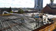 A concrete slab with reinforced steel. Workers pour concrete onto the slab